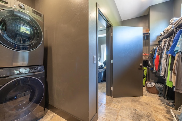 washroom featuring stacked washer / drying machine and stone tile floors