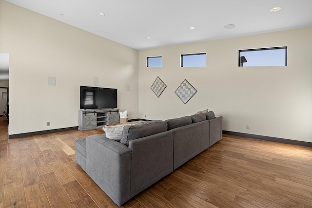 living room with wood finished floors, baseboards, and recessed lighting