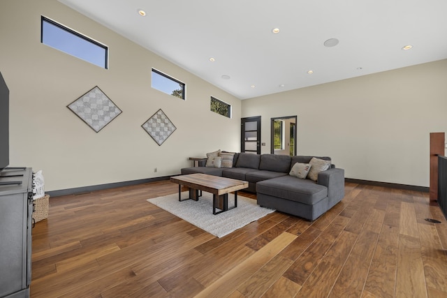 living room featuring hardwood / wood-style floors, healthy amount of natural light, recessed lighting, baseboards, and a towering ceiling