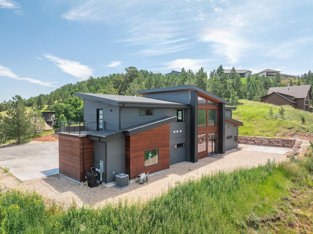 rear view of property with gravel driveway and central air condition unit