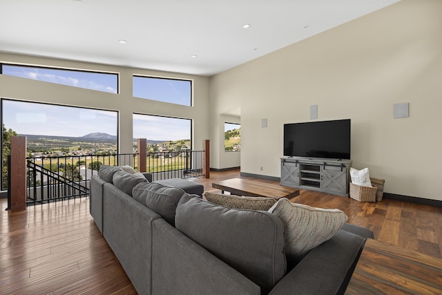 living area featuring baseboards, a towering ceiling, wood finished floors, and recessed lighting