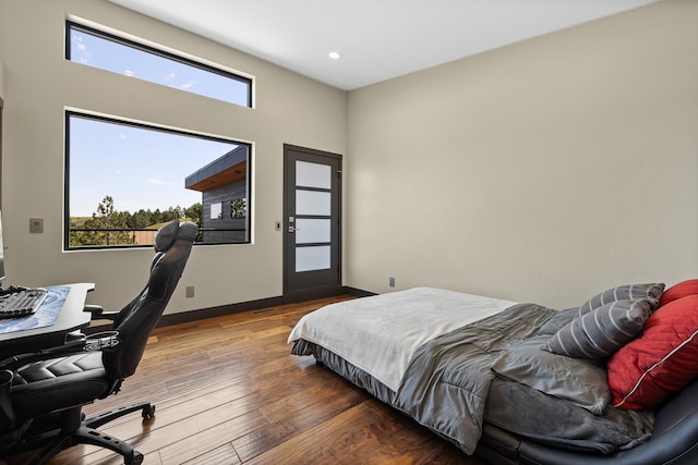 bedroom with wood finished floors, an office area, baseboards, and recessed lighting