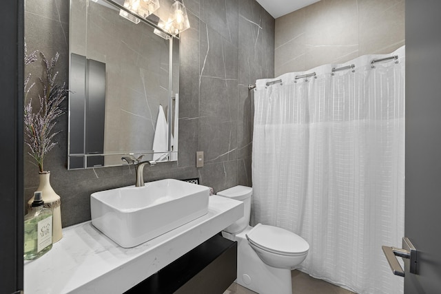 full bath featuring tile walls, a sink, toilet, and curtained shower