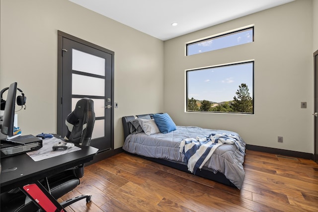 bedroom featuring hardwood / wood-style floors, an office area, recessed lighting, and baseboards
