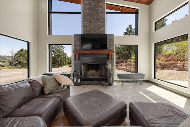living room featuring a towering ceiling, stone tile flooring, a fireplace, and baseboards