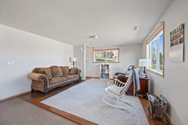 living room featuring a textured ceiling, wood finished floors, and baseboards