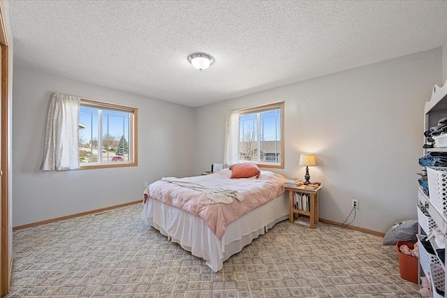 bedroom with baseboards, a textured ceiling, and light carpet