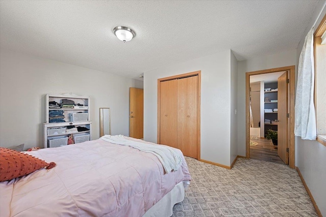 carpeted bedroom featuring a textured ceiling, baseboards, and a closet