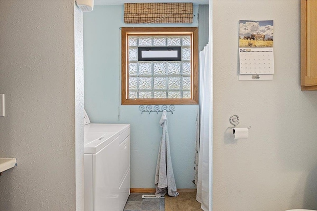 clothes washing area with separate washer and dryer and baseboards