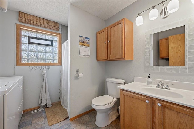 bathroom with washing machine and clothes dryer, toilet, baseboards, vanity, and a textured ceiling