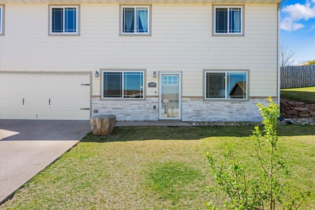 view of front of property featuring stone siding, driveway, and a garage