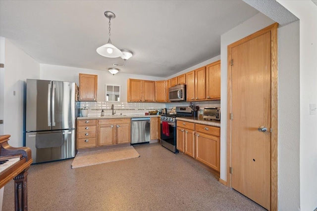 kitchen with appliances with stainless steel finishes, a sink, light countertops, tasteful backsplash, and hanging light fixtures