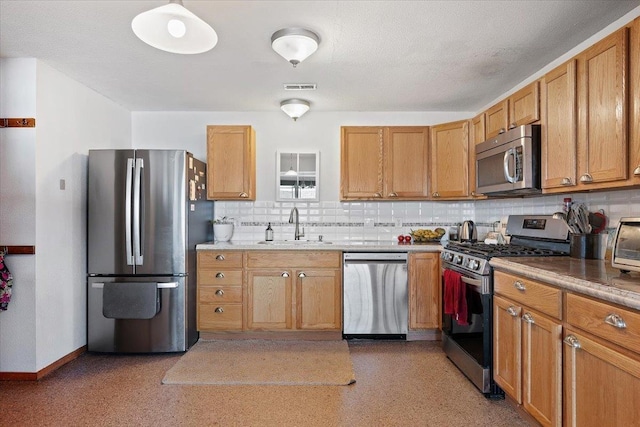 kitchen with stainless steel appliances, a sink, tasteful backsplash, baseboards, and brown cabinetry