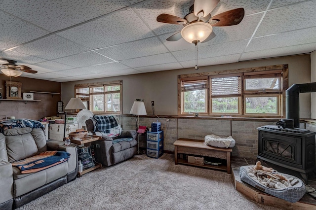 12944 Larene Dr, Black Hawk, SD 57718 - carpeted living room featuring a ceiling fan, a wood stove, a drop ceiling, and a wainscoted wall