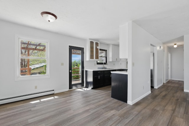 5753 Pluto St, Rapid City, SD 57703 - kitchen featuring a sink, light countertops, wood finished floors, glass insert cabinets, and baseboards