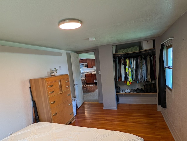 bedroom featuring wood finished floors, a closet, and baseboards