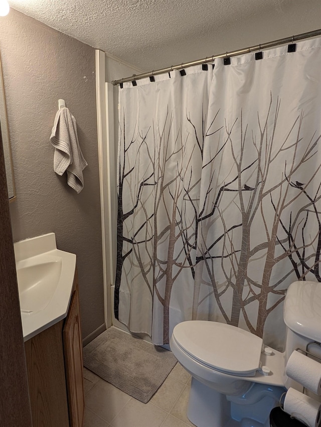 bathroom with a textured wall, a textured ceiling, toilet, vanity, and tile patterned flooring