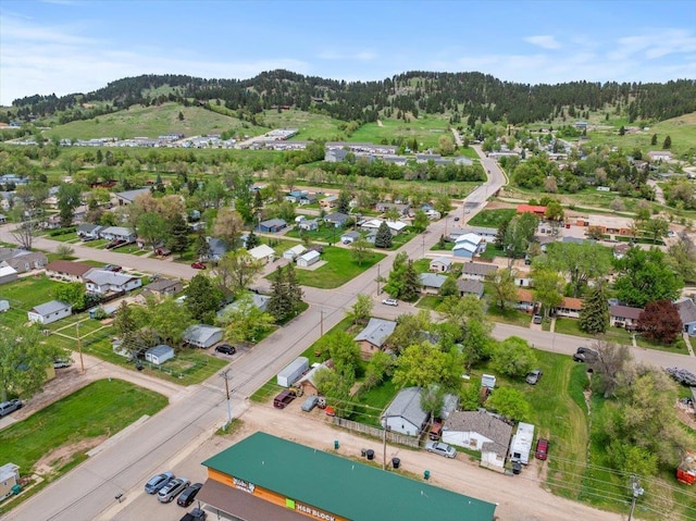 aerial view of property and surrounding area with a heavily wooded area and nearby suburban area