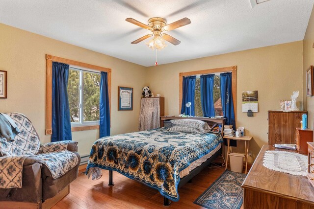 2030 12th Ave, Belle Fourche, SD 57717 - bedroom featuring wood finished floors, baseboard heating, and ceiling fan