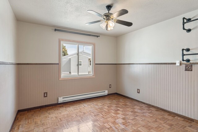 2030 12th Ave, Belle Fourche, SD 57717 - spare room with a baseboard radiator, a wainscoted wall, a textured ceiling, baseboards, and ceiling fan
