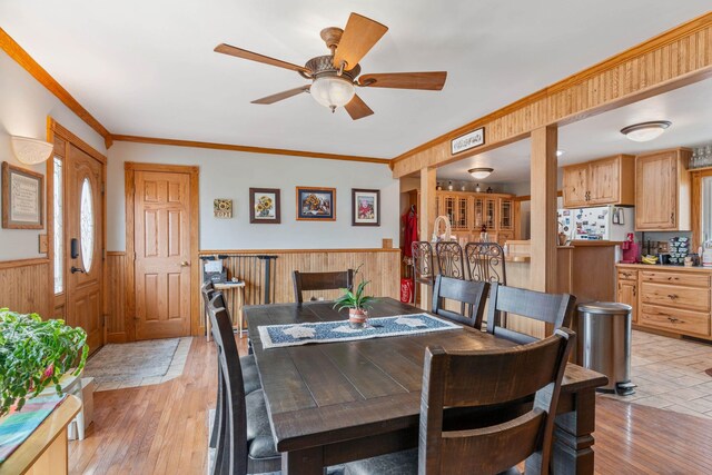 2030 12th Ave, Belle Fourche, SD 57717 - dining space with wainscoting, light wood finished floors, a ceiling fan, ornamental molding, and wood walls
