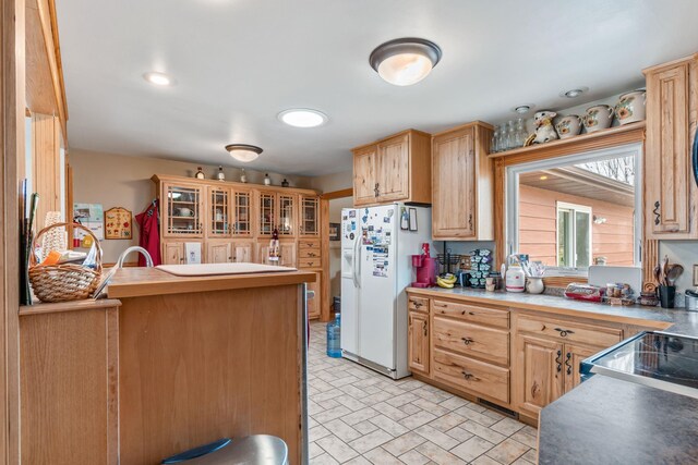 2030 12th Ave, Belle Fourche, SD 57717 - kitchen with white refrigerator with ice dispenser, light brown cabinetry, glass insert cabinets, a peninsula, and brick patterned floors