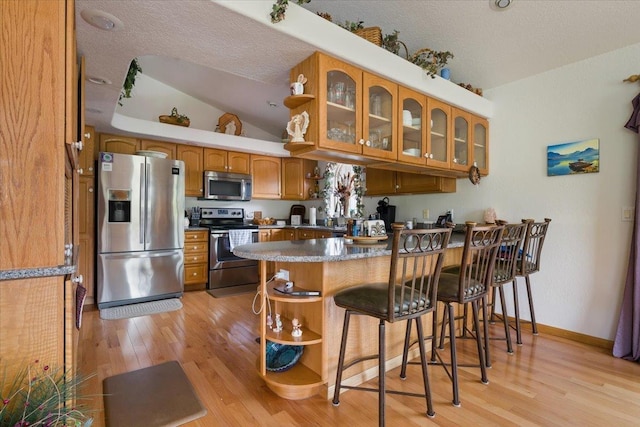 1129 Foothills Rd, Sturgis, SD 57785 - kitchen featuring appliances with stainless steel finishes, a peninsula, light wood-type flooring, glass insert cabinets, and open shelves