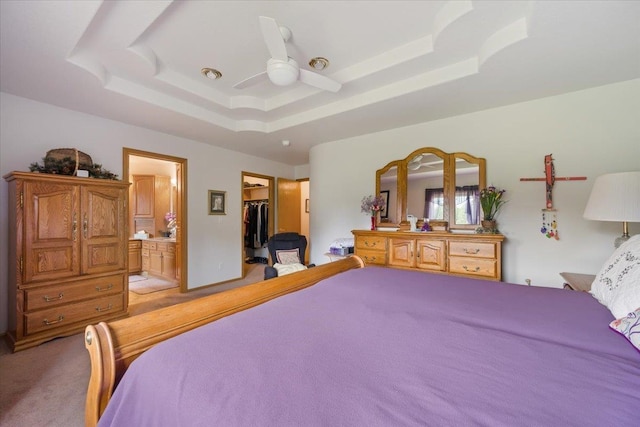 1129 Foothills Rd, Sturgis, SD 57785 - bedroom with a tray ceiling, light colored carpet, a walk in closet, connected bathroom, and a ceiling fan