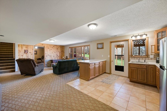 376 Lone Elk Rd, Spearfish, SD 57783 - kitchen featuring a sink, light countertops, a peninsula, glass insert cabinets, and wooden walls