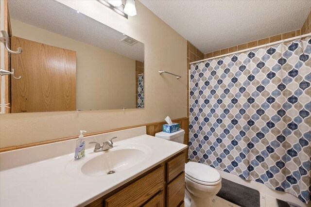 376 Lone Elk Rd, Spearfish, SD 57783 - bathroom with a textured ceiling, toilet, curtained shower, and vanity