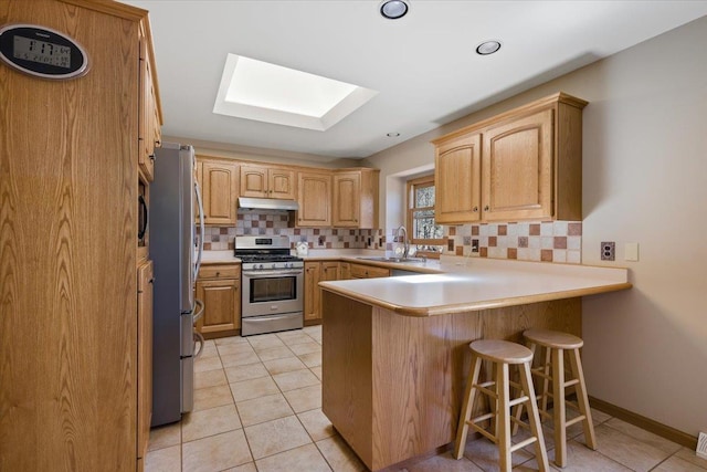376 Lone Elk Rd, Spearfish, SD 57783 - kitchen featuring stainless steel appliances, under cabinet range hood, a peninsula, a skylight, and tasteful backsplash