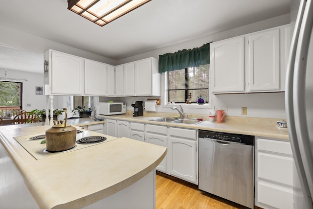 24227 Pine Grove Rd, Rapid City, SD 57702 - kitchen featuring stainless steel dishwasher, a sink, white microwave, fridge, and white cabinetry