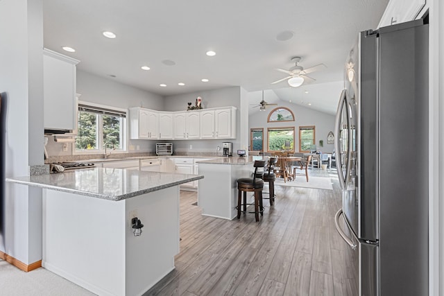 7725 Other, Rapid City, SD 57702 - kitchen featuring freestanding refrigerator, a peninsula, a ceiling fan, white cabinets, and vaulted ceiling
