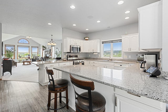 7725 Other, Rapid City, SD 57702 - kitchen with appliances with stainless steel finishes, a peninsula, a sink, white cabinets, and light stone countertops