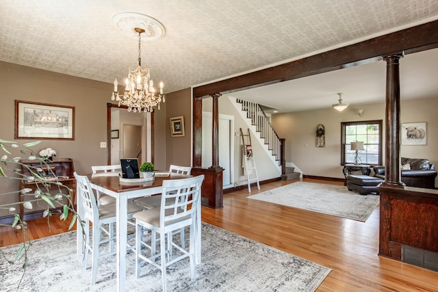 8510 Clarkson Rd, Rapid City, SD 57702 - dining room featuring ornate columns, light wood-style floors, a chandelier, and stairs