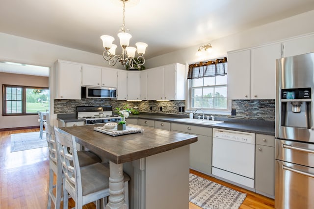 8510 Clarkson Rd, Rapid City, SD 57702 - kitchen featuring appliances with stainless steel finishes, a sink, tasteful backsplash, light wood-type flooring, and a chandelier