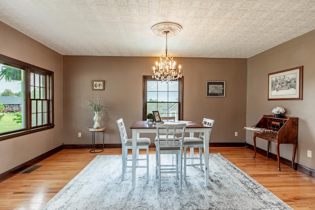8510 Clarkson Rd, Rapid City, SD 57702 - dining area with a chandelier, light wood-style flooring, plenty of natural light, and a textured ceiling