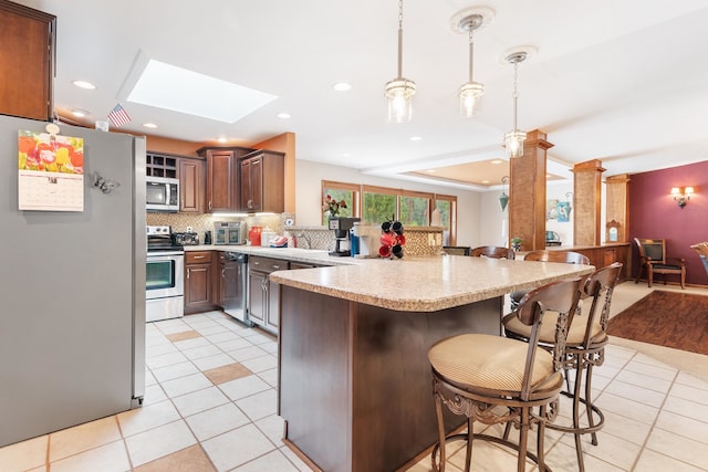 22994 Shields Rd, Rapid City, SD 57702 - kitchen featuring stainless steel appliances, a peninsula, light countertops, light tile patterned floors, and a kitchen bar