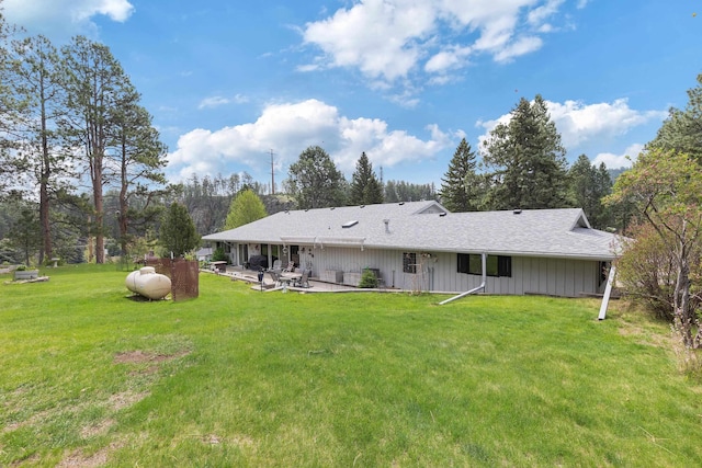 22994 Shields Rd, Rapid City, SD 57702 - rear view of property featuring a lawn, a patio, a shingled roof, and view of wooded area