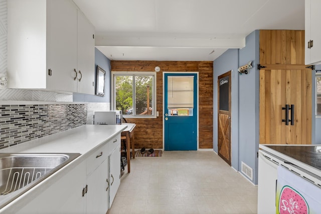 2101 Juniper Dr, Rapid City, SD 57702 - kitchen with wooden walls, white cabinets, decorative backsplash, light countertops, and a sink