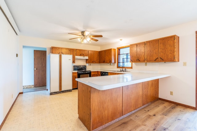 15630 Antelope Creek Rd, Rapid City, SD 57703 - kitchen featuring black appliances, under cabinet range hood, brown cabinetry, a peninsula, and light countertops