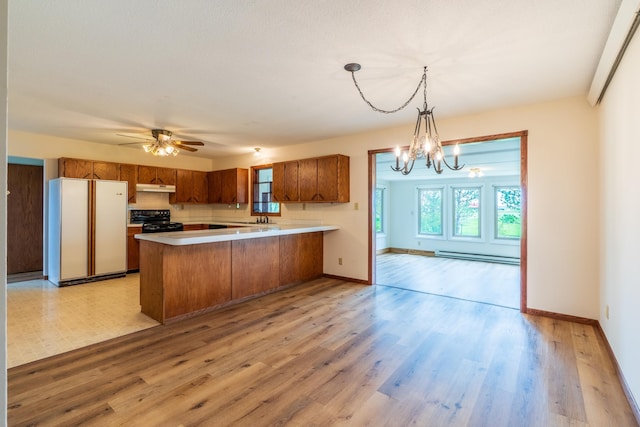15630 Antelope Creek Rd, Rapid City, SD 57703 - kitchen with freestanding refrigerator, brown cabinets, black stove, a peninsula, and under cabinet range hood