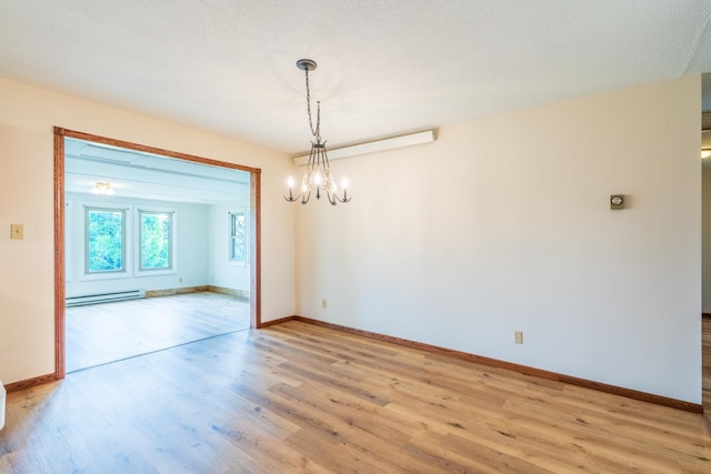 15630 Antelope Creek Rd, Rapid City, SD 57703 - spare room featuring a baseboard heating unit, light wood-style flooring, a chandelier, and baseboards
