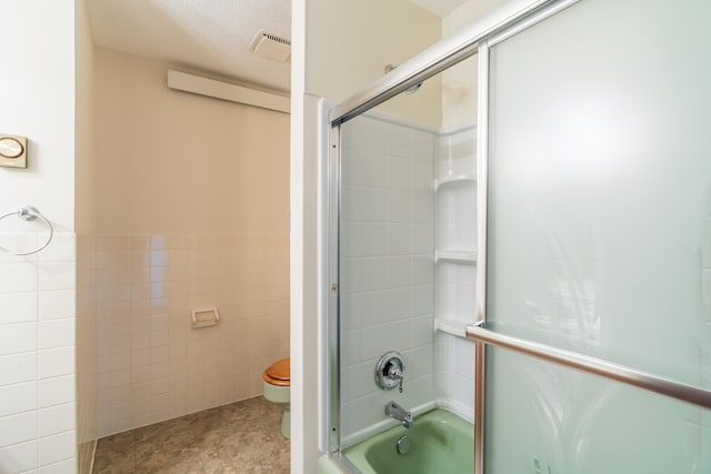 15630 Antelope Creek Rd, Rapid City, SD 57703 - bathroom featuring tile walls, toilet, enclosed tub / shower combo, tile patterned flooring, and a wainscoted wall