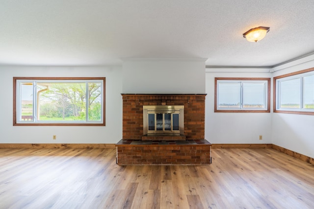 15630 Antelope Creek Rd, Rapid City, SD 57703 - unfurnished living room featuring wood finished floors, a brick fireplace, baseboards, and a textured ceiling
