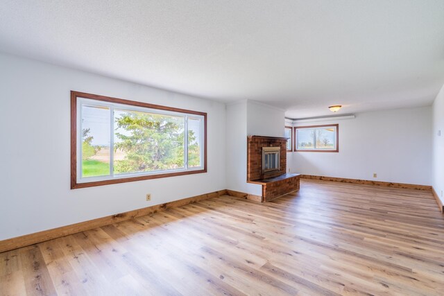 15630 Antelope Creek Rd, Rapid City, SD 57703 - unfurnished living room featuring wood finished floors, healthy amount of natural light, baseboards, and a fireplace