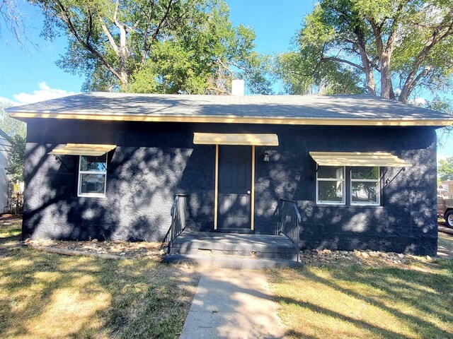 105 N Washington St, Edgemont, SD 57735 - ranch-style house with a front lawn, stucco siding, a chimney, and a shingled roof