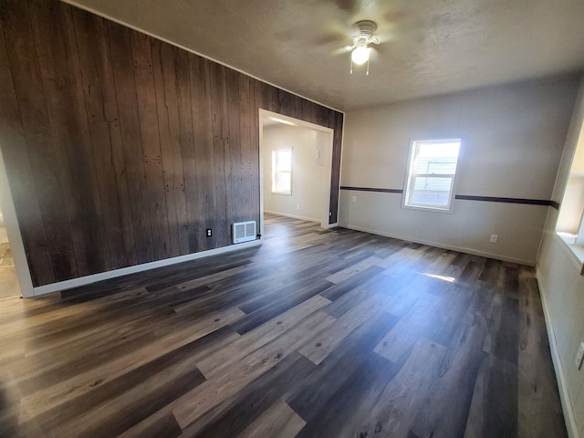 105 N Washington St, Edgemont, SD 57735 - spare room with a ceiling fan, healthy amount of natural light, dark wood-style floors, baseboards, and wood walls