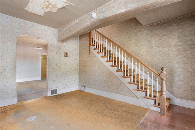 308 Main St, Deadwood, SD 57732 - stairs featuring wallpapered walls, wood finished floors, arched walkways, and baseboards