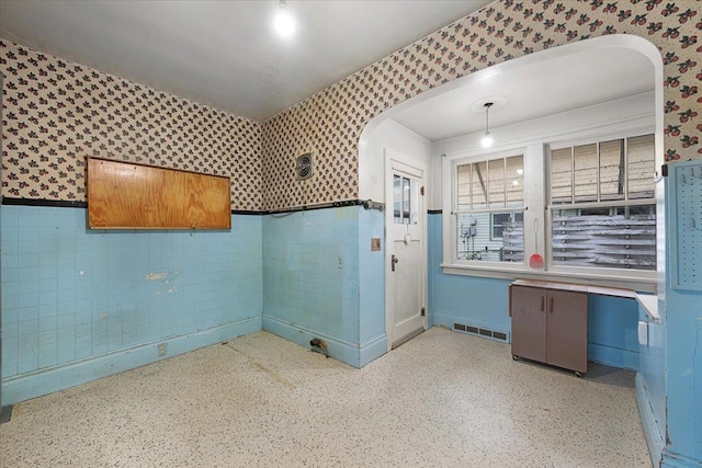 308 Main St, Deadwood, SD 57732 - empty room featuring wallpapered walls, a wainscoted wall, arched walkways, and speckled floor